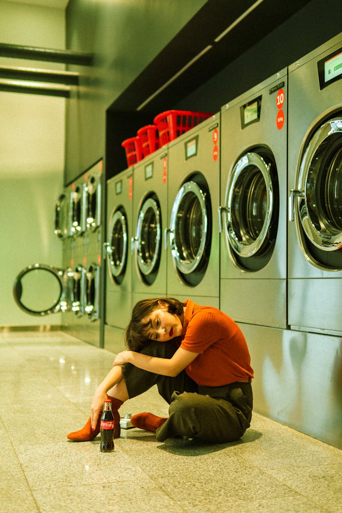 A young woman sitting by laundromat machines with a soda bottle in Baku, Azerbaijan.